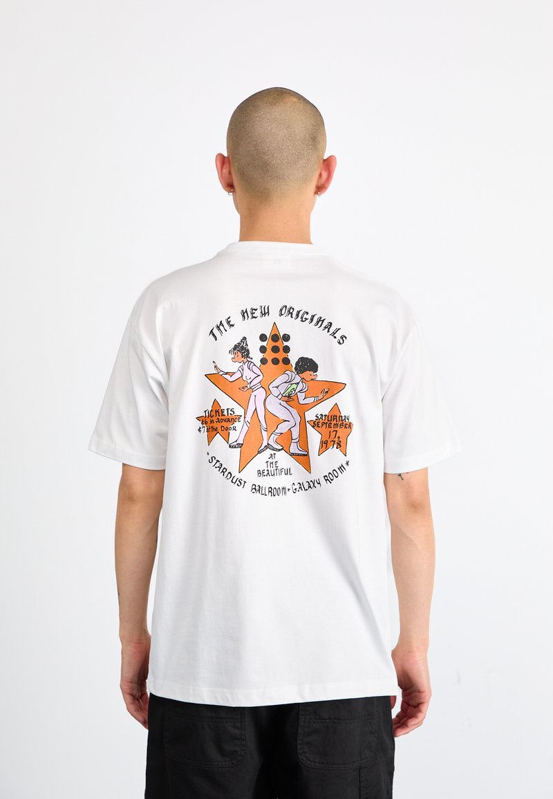 Hvit bomull t-skjorte med en fargerik grafikk på baksiden, med en stjernes form, to figurer og retro tekstdetaljer i oransje og svart.