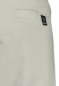 Beige katoenen broek met een achterzak en een zwart label met de tekst "HEY LARGO." Soepele textuur en getailleerde pasvorm.