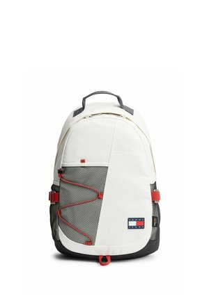 Sac à dos blanc et noir avec des touches rouges, poche avant en mesh, sangles latérales réglables et un écusson logo Tommy Jeans sur la partie basse avant.
