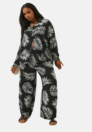 Ensemble de vêtements de détente à motif de feuilles noir et blanc comprenant une chemise à boutonnage et un pantalon large ; tissu léger avec une coupe décontractée et une taille à cordon.