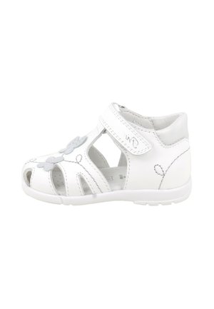 Sandalo bianco per bambino piccolo con intagli floreali, cinturino in velcro e supporto imbottito per la caviglia, mostrato su sfondo bianco.