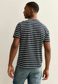 Striped t-shirt in black and white cotton, featuring short sleeves and a crew neckline. Worn with faded blue jeans.