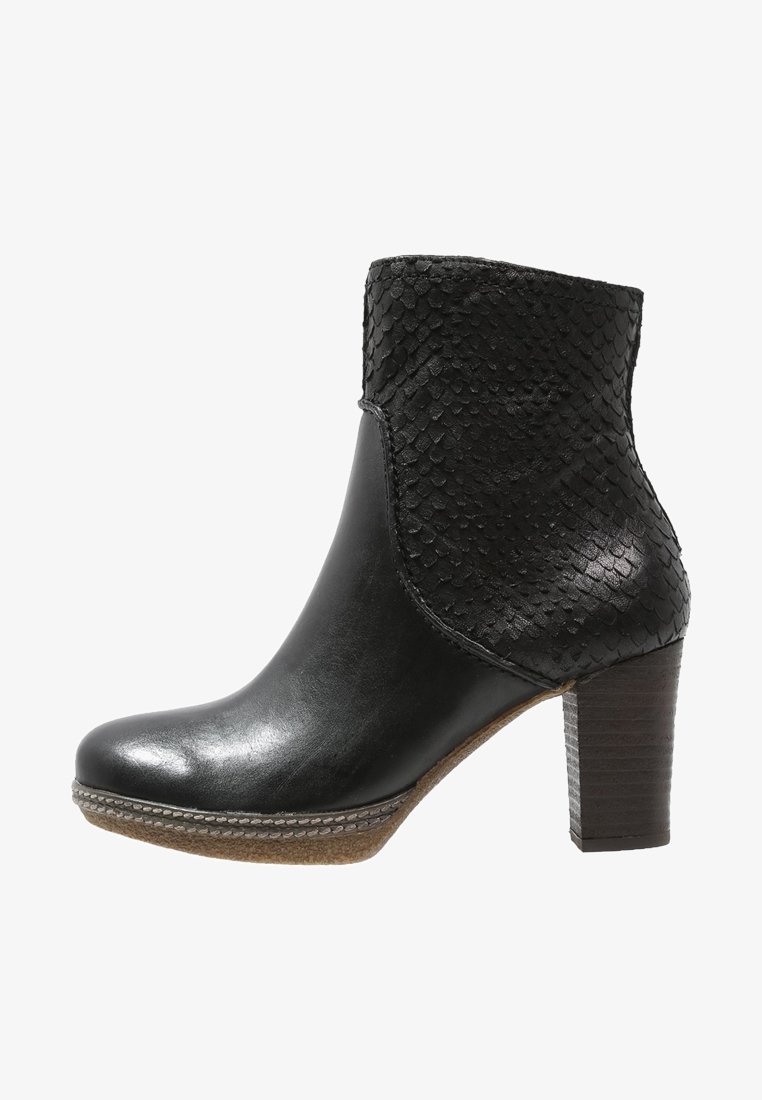 Bottine noire à la cheville avec tige texturée, bout en cuir lisse, talon bloc empilé et détail de couture sur la semelle, sur fond blanc.