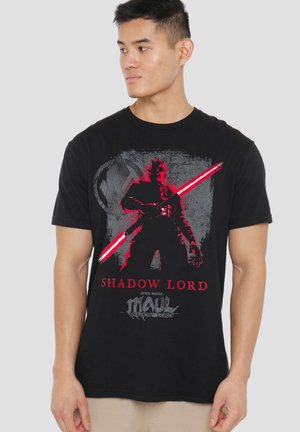 Man wearing black t-shirt with red and gray graphic of Star Wars character holding a double red lightsaber, text "Shadow Lord."