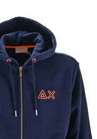 Felpa con zip di colore blu navy, con cappuccio, lacci e simboli triangolari e a X ricamati in arancione sul petto.