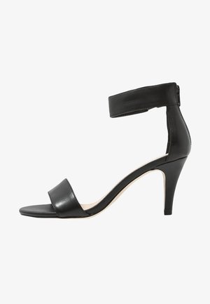 Černé sandály na vysokém podpatku s páskem kolem kotníku a otevřenou špičkou, které mají elegantní design a lesklý povrch.