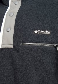 Maglione in pile nero con collo grigio con bottoni, tasca frontale con zip e logo Columbia Sportswear. Tessuto strutturato, design casual.