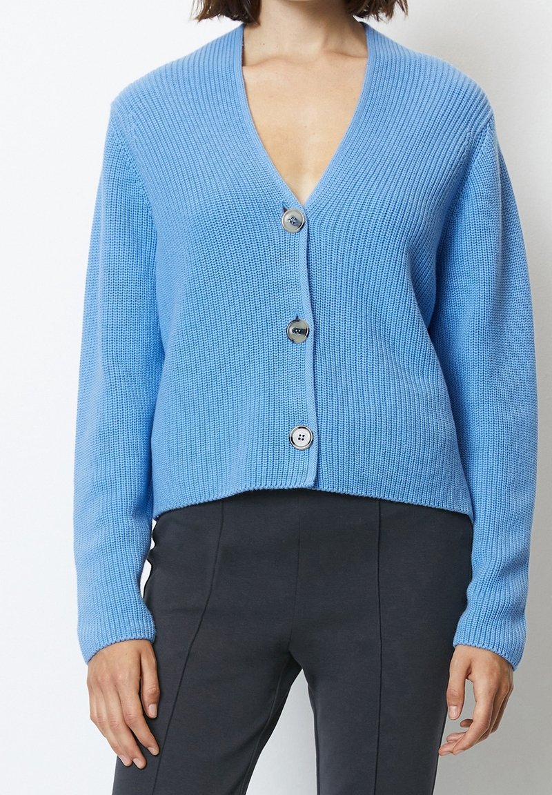 Ljusblå cardigan i ribbat stickat med V-hals, med tre stora runda knappar framtill och en kortad nederkant.