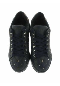 Czarne pikowane skórzane sneakersy z czarnymi sznurówkami, złotymi ćwiekami i wytłoczonym napisem "GUESS" na języku, widok z góry.