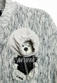 Cárdigan de punto gris de gran tamaño con un motivo de oso, capucha gris y detalle de cadena plateada. Tejido texturizado con rayas verticales.
