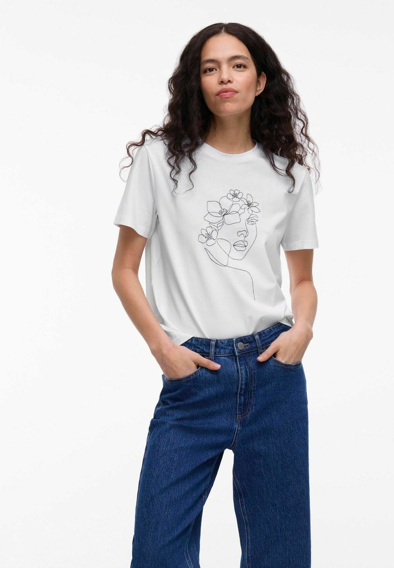 Witte katoenen T-shirt met een minimalistische zwarte lijntekening van een gezicht versierd met bloemen, gedragen met hoogzittende blauwe denim jeans.