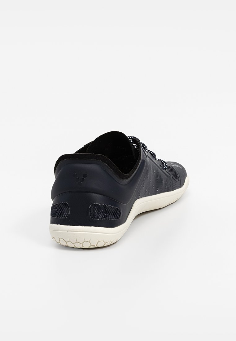 Zapatilla deportiva negra con un upper sintético texturizado, puntera redonda, cierre de cordones y una suela exterior de goma blanca con un patrón en forma de panal.