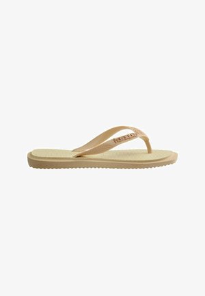 Tan flip-flop sandaal met een textuur voetbed, dunne bandjes en logo detail. Gemaakt van flexibel materiaal met een geribbelde buitenzool voor grip.