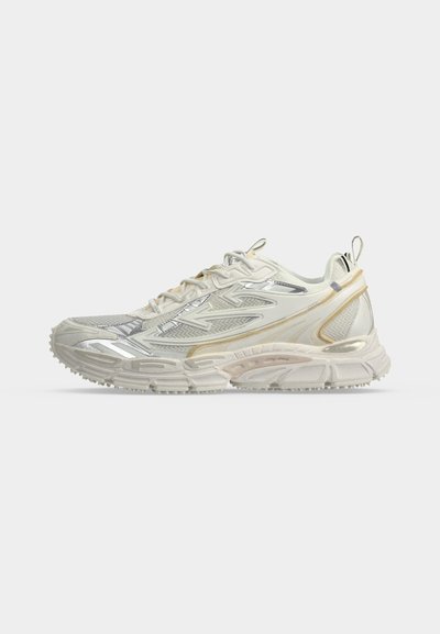 Chaussure de sport blanc cassé avec des empiècements en mesh et en synthétique, semelle épaisse texturée et fermeture à lacets, vue de côté extérieur.