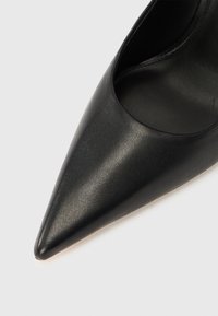 Svart pumps i skinn med spiss tupp og en elegant finish, med utskjæringer på sidene og glatt tekstur.