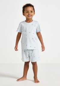 Completo pigiama in cotone azzurro chiaro, composto da una maglietta a maniche corte e pantaloncini, decorato con piccoli motivi di barche in rosso e blu.