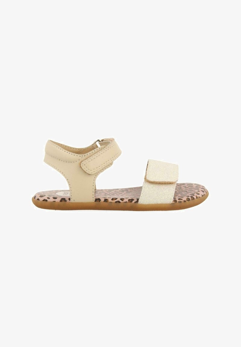 Sandalia beige con una correa de Velcro y un acento dorado brillante. Presenta una plantilla con estampado de leopardo y una suela de goma flexible y texturizada.