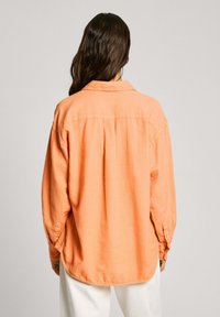Orange Button-Up-Hemd mit lässiger Passform, langen Ärmeln und weichem Material. Verfügt über einen klassischen Kragen und abgerundeten Saum.