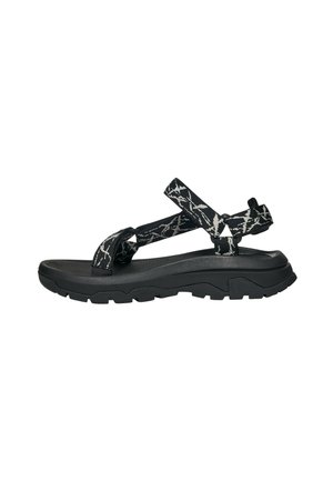 Zwart-wit gemusterde sandalen met verstelbare stoffen straps, een getextureerde voetbed en een robuuste zwarte rubberen zool met gripgroeven.