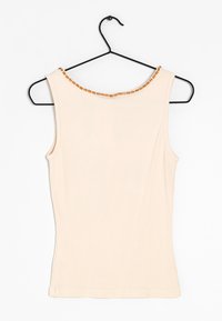 Béžové tílko s žebrovanou texturou, zdobené ozdobnou linií malých hnědých korálků kolem kulatého výstřihu. Visí na černém háčku.