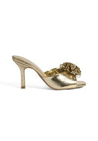 Gouden metallic open teen muiltjes met een unieke gekrulde bloemdetail op de bovenkant, een slanke hoge hak en een gladde textuur.