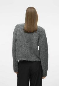 Grå strikket genser med en cropped design, rillede detaljer på ermene, og myk tekstur. Kombinert med svarte bukser, sett fra baksiden.