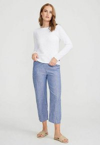 Witte lange mouwtop met een textuurafwerking, gecombineerd met blauw-wit gestreepte cropped broek, met een ontspannen pasvorm en eenvoudig ontwerp.