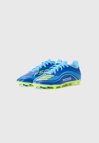 Scarpe da calcio blu con accenti verdi, dotate di una tomaia sintetica liscia, un evidente marchio "MESSI" e tacchetti stampati per una migliore trazione.