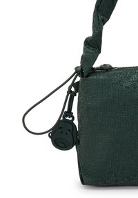 Borsa verde con texture e finitura lucida, dotata di una superficie con un motivo e un charm a forma di faccia di cartone animato. Decorata con un manico annodato.