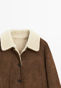 Bruine nepleren suède jas met een crèmekleurige schapenwollen kraag, voorzien van vier knopen aan de voorkant en twee zijzakken. Zachte textuur en warm ontwerp.