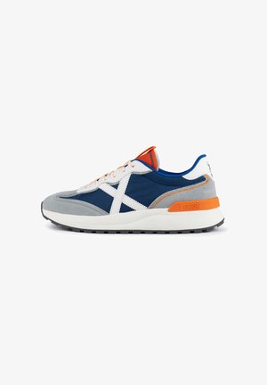 Baskets pour hommes avec un dessus en daim gris et maille bleu marine, accents blancs, étiquette de talon orange, semelle en caoutchouc et lacets contrastants.