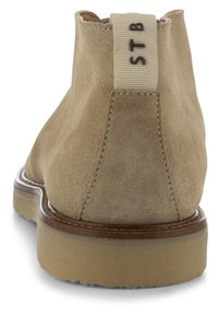 Stivali ankle in suede beige chiaro con finitura testurizzata, punta rotonda e suola in gomma leggera. Presentano un'etichetta in tessuto con la scritta "STB.".