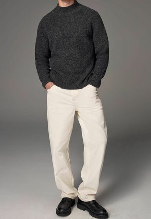 Dark gray knitted sweater with high neckline, paired with off-white wide-leg pants and black lace-up shoes. Smooth texture and relaxed fit.