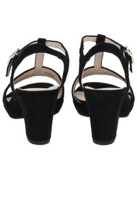 Černé semišové lodičky s robustním podpatkem, otevřenou patou a náramkem kolem kotníku, který zdobí stříbrná spona. Hladká podšívka a strukturovaný vnější povrch.