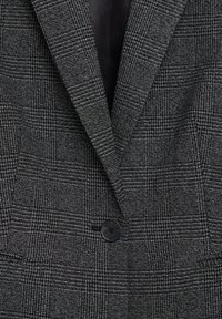 Blazer gris texturé avec un motif à carreaux, revers crantés et une fermeture à un seul bouton noir. L'intérieur possède une doublure lisse.