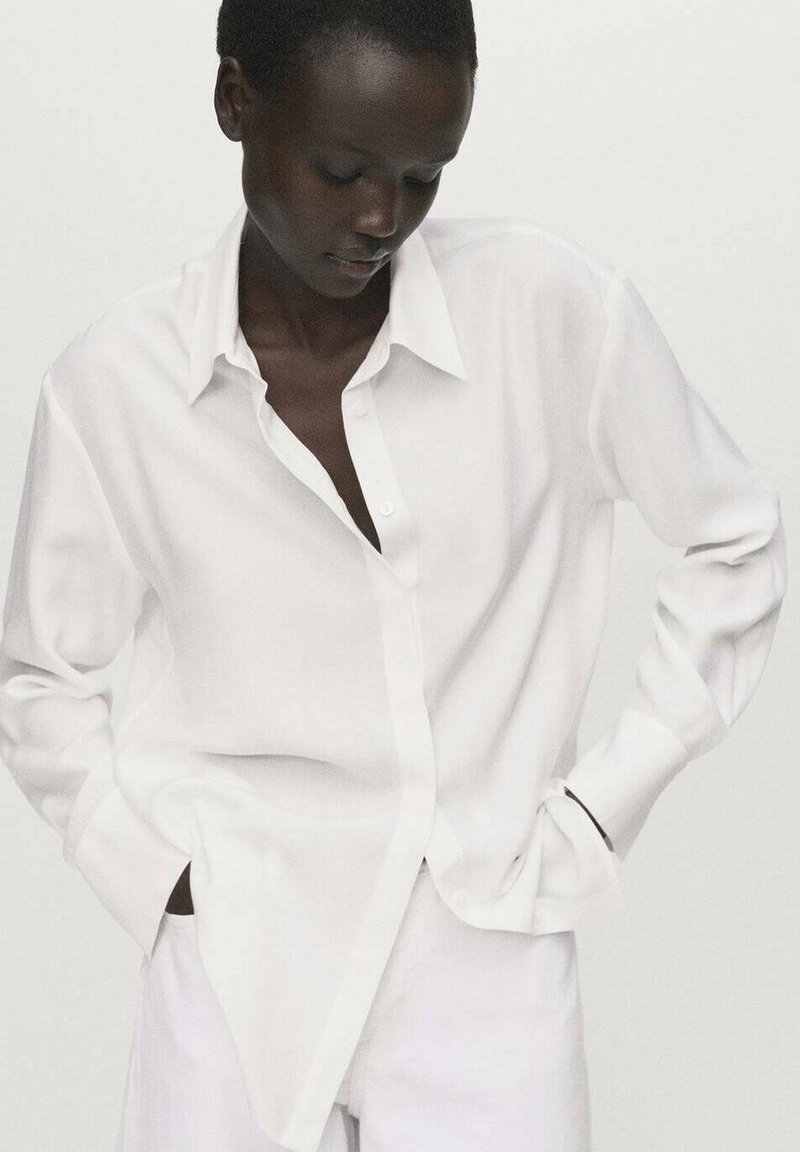 White button-up shirt with a relaxed fit, long sleeves, and a classic collar. Made of lightweight fabric, featuring a smooth texture.