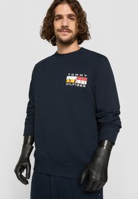 Marine sweatshirt med et flerfarget logo-patch med "TOMMY HILFIGER." Ribbestrikkede mansjetter og midjebånd, strukturert fasong, myk stoff.