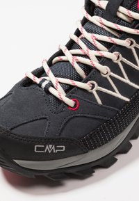 Black suede hiking shoe with mesh accents, reflective details, and cream-red laces. Features textured rubber sole and CMP logo.