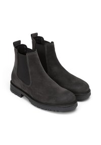 Une paire de bottes Chelsea en daim noir avec des panneaux élastiques sur les côtés et des languettes de traction, dotées de semelles en caoutchouc épaisses et de bouts ronds.