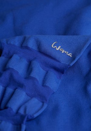 Blauwe katoenen stof met een gegolfd ontwerp en een zilveren "Woma" logo, met een soepele textuur en levendige kleur.