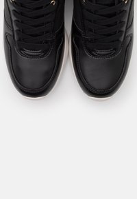 Svarta lädersneakers med en slät struktur, rund tå och tjock vit sula. Sex svarta snörhål håller matchande snören, med subtila sömnadsdetaljer.