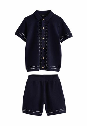 Marineblaues, gestricktes Kurzarmhemd mit Knöpfen und passenden gestrickten Shorts mit weißen Ziernähten.