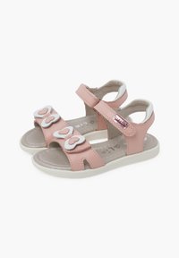 Sandalias sintéticas rosas que presentan tres acentos en forma de corazón blancos, correa de velcro, diseño de talón abierto y una suela texturizada.