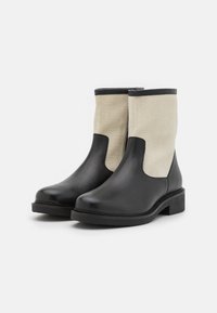 Botas de tornozelo em couro preto com painéis em lona bege, bico arredondado e salto bloco baixo. Apresenta costura e acabamento contrastante ao redor das bordas.