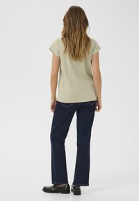 Ljust grönt kortärmat linne parat med mörkblå jeans och svarta skor, med en avslappnad passform och enkel design.