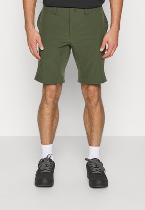 Olive-green shorts made of lightweight fabric, featuring a standard waist, side pockets, and a fold-up hem. Worn with black sneakers and white socks.