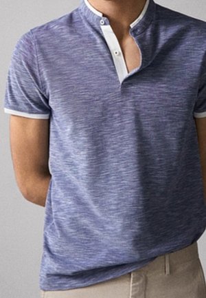 Homme portant un polo à manches courtes bleu chiné avec une bordure blanche et un bas beige, debout sur un fond uni.