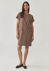 Brown, short-sleeve dress with a crew neckline, featuring two front pockets with gold buttons. Smooth fabric, knee-length cut, minimalist design.
