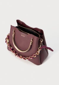 Sac à main en cuir mauve avec une forme structurée, quincaillerie dorée et une anse en chaîne accentuée par un tissu violet. Comprend deux compartiments zippés.