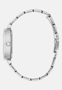 Hõbedane metallkell ümmarguse korpuse ja lingibraceti ning silmapaistmatu viimistlusega. Rihma pind on siledalt poleeritud ja sellel on peened detailid.